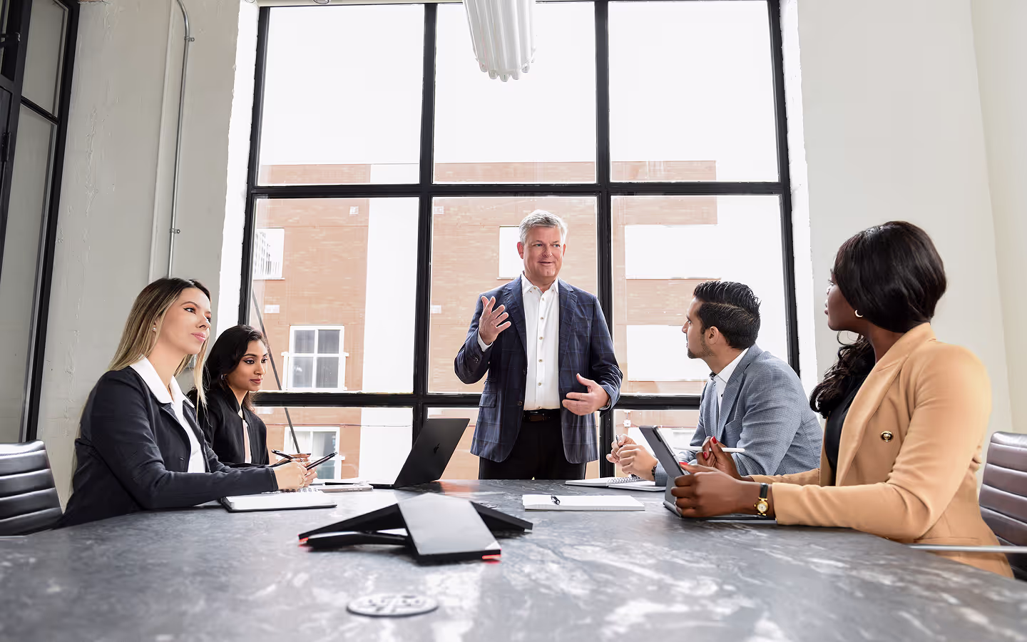 Group of people gathered around an office table, engaged in a discussion and brainstorming ideas.